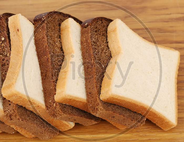 White And Brown Loaf Of Bread On Wooden Table. Whole Background.