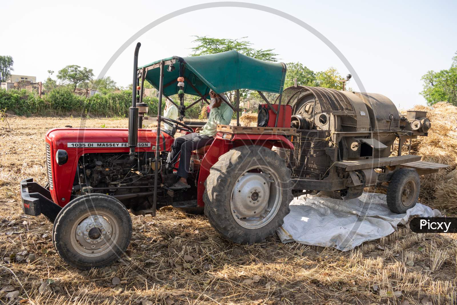 Indian farmers use threshing machine after harvesting the wheat crop