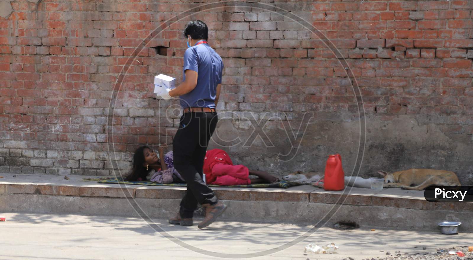 A Man Distributes Food To Homeless Woman During Nationwide Lockdown In Wake Of Coronavirus or COVID-19  Pandemic In Prayagraj, March 12, 2020.