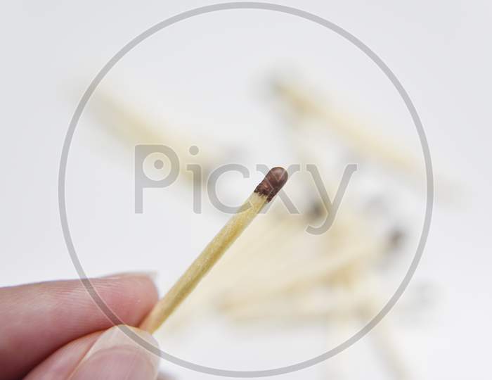 Wooden Match In The Hand With Matches On The White Backgtound. Selective Focus. Chain Reaction Concept.