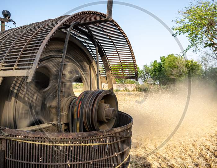 Wheat straw comes out of thresher machine as Indian farmers use machine for threshing after harvesting wheat crop