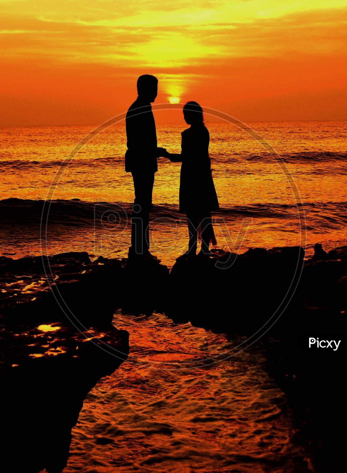 Silhouette of Lover Couple Over a Beach With Sunset Sky in Background