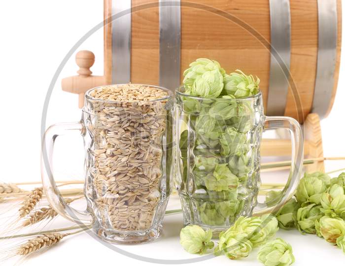 Close Up Of Beer Mugs. Isolated On Barrel And Hop Background.
