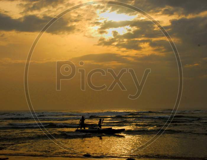Silhouette of Fisherman Going For Fishing in Boats Over a Sea With Sunset Sky in Background