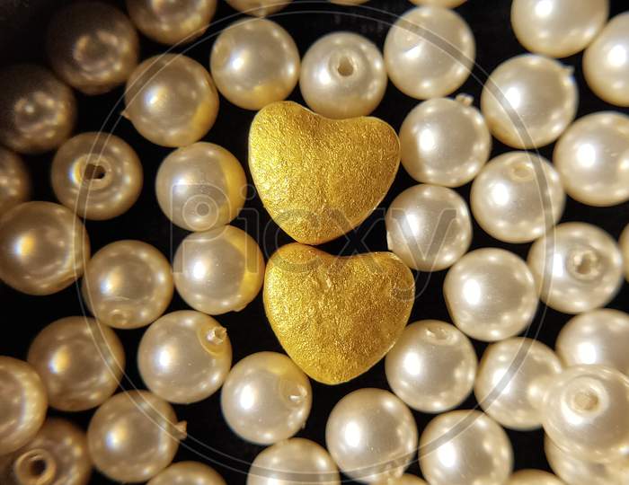 American pearls with heart shaped objects. Golden hearts and pearls. Close up of pearls.