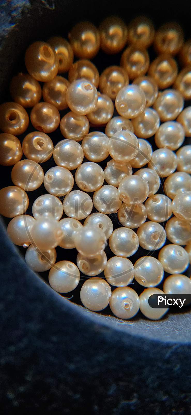 American pearls close up. Golden colour pearls on black background.
