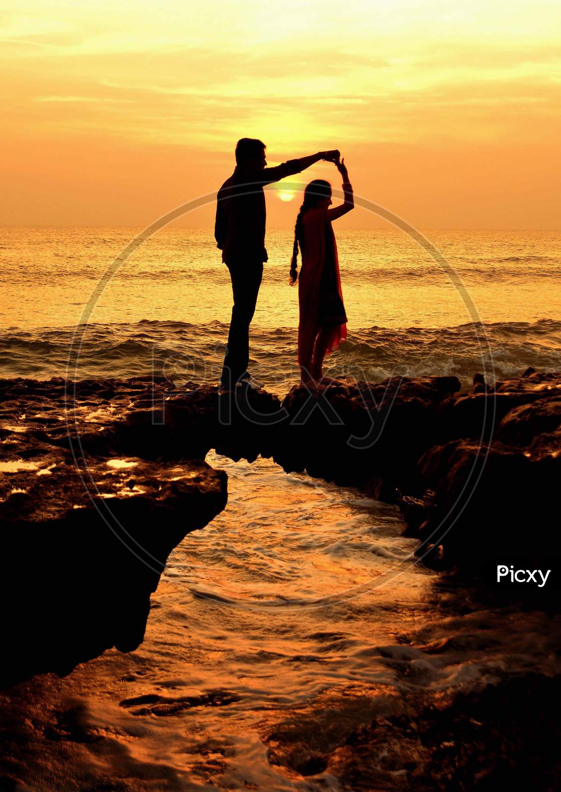 Silhouette of Lover Couple Over a Beach With Sunset Sky in Background
