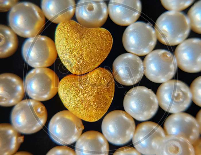 American pearls with heart shaped objects. Golden hearts and pearls. Close up of pearls.