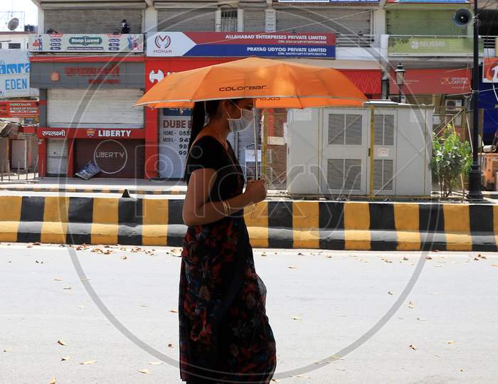 A Woman Use Umbrella Walk On The Empty Road During Nationwide Lockdown In Wake Of Coronavirus or covid-19  Pandemic In Prayagraj, March 13, 2020.