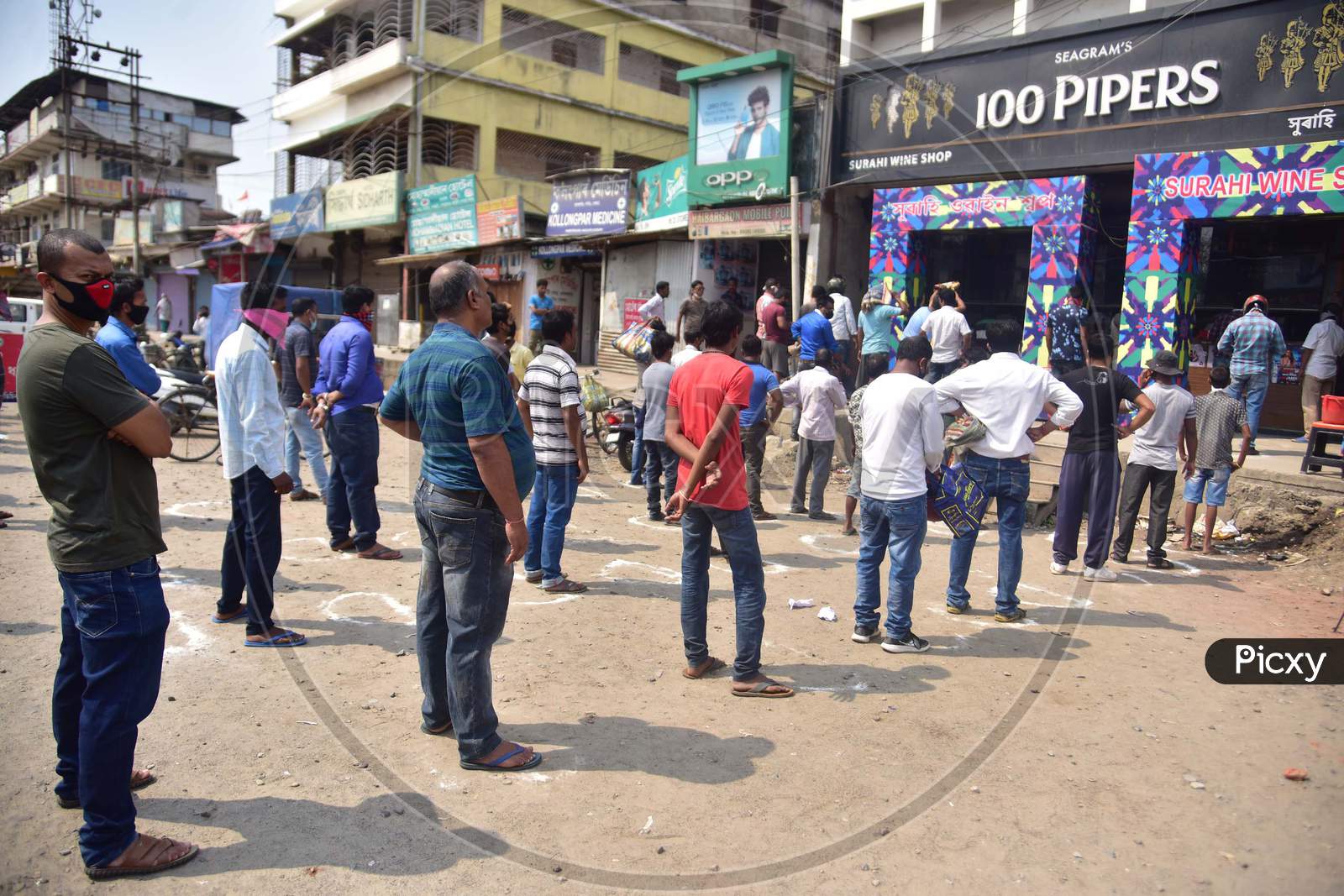 People Maintain Social Distance As They Stand In A Queue Outside A Wine Shop, During The Nationwide Lockdown To Curb The Spread Of Coronavirus or Covid-19 , In Nagaon District Of Assam Monday, April 13, 2020.