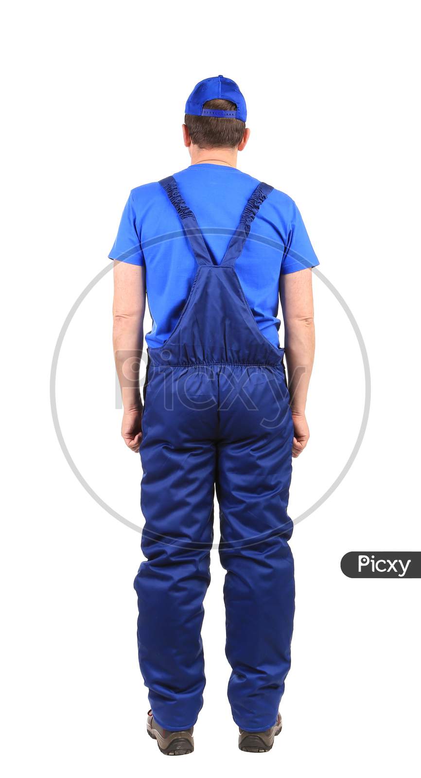 Worker In Blue Overalls. Back View. Isolated On A White Background.
