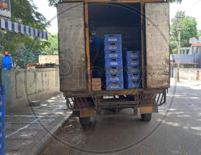 Van parked with crates of milk beside retail shop