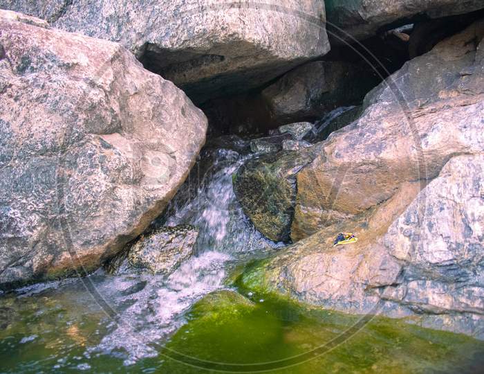 Water Flowing Out From The Rocks With Green Moss On The Sides