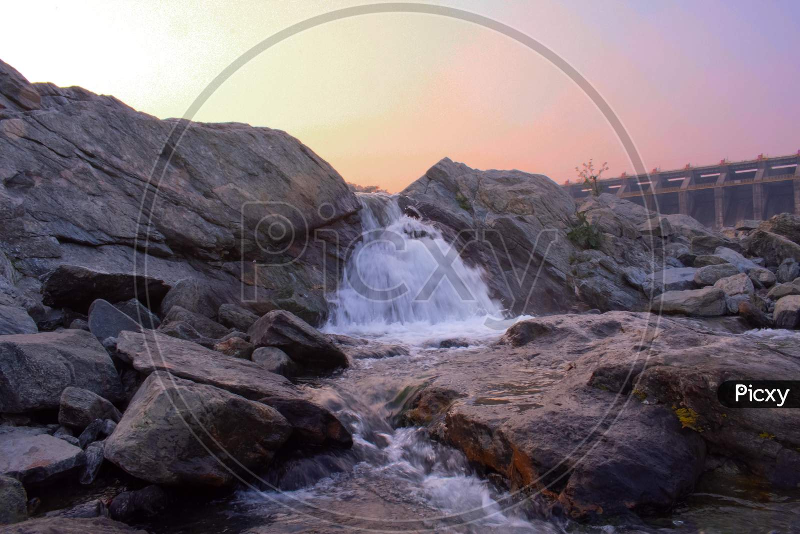 A Small Waterfall Flowing Between The Rocks During Sunset