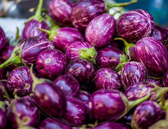 Top-Down View Of A Heap Of Brinjals On Market .The Name As Called Egg Fruit, Aubergine, Solanum Melongena For Sale In A Vegetable Market. Overhead Composition And Top View. Indian Street Market