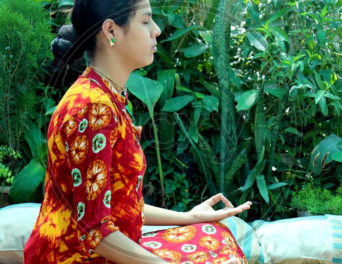 Indian woman doing meditation, yoga exercise at home garden during lockdown  due to Coronavirus or covid-19