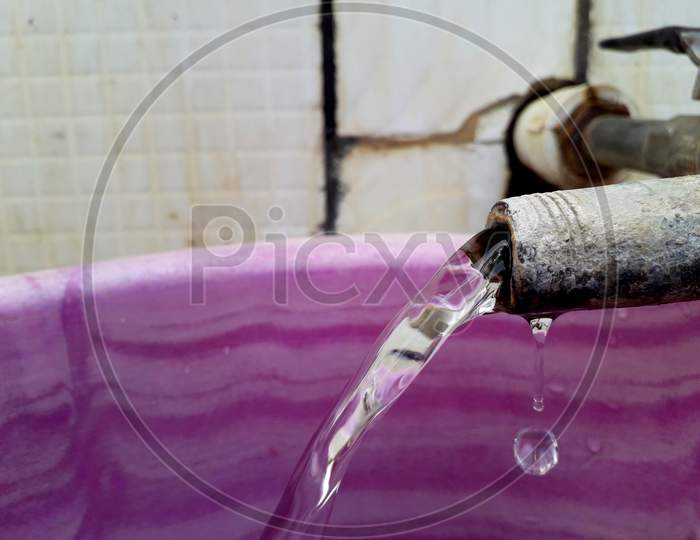 Water squirt or flow coming out from a tap and going to bucket with falling down water drops