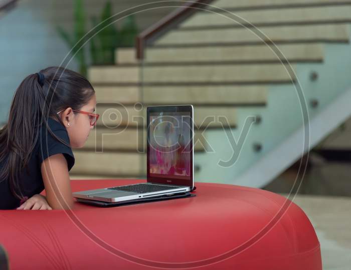 A Kid learning from laptop while relaxed on a sofa.