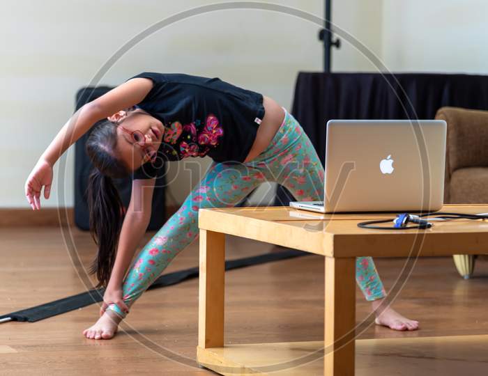 a girl performing yoga and doing meditation as instructed by her teacher through e learning platform