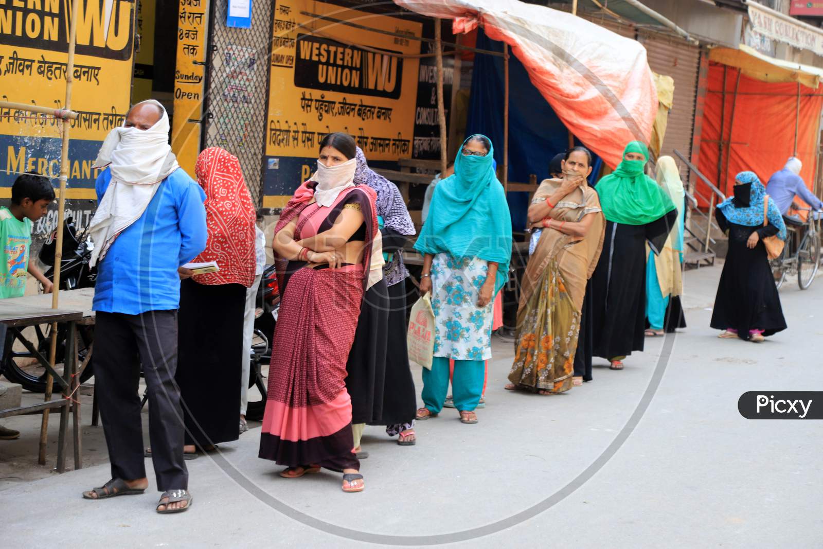 People Stand In A Queue to Withdraw Money Outside Of A Bank During A Nationwide Lockdown To Slow The Spreading Of The Coronavirus Disease (Covid-19), In Prayagraj, April, 16, 2020.