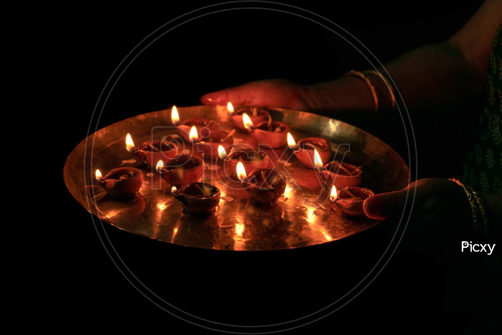 Indian woman performing worship along with lighting oil lamp (Diya)