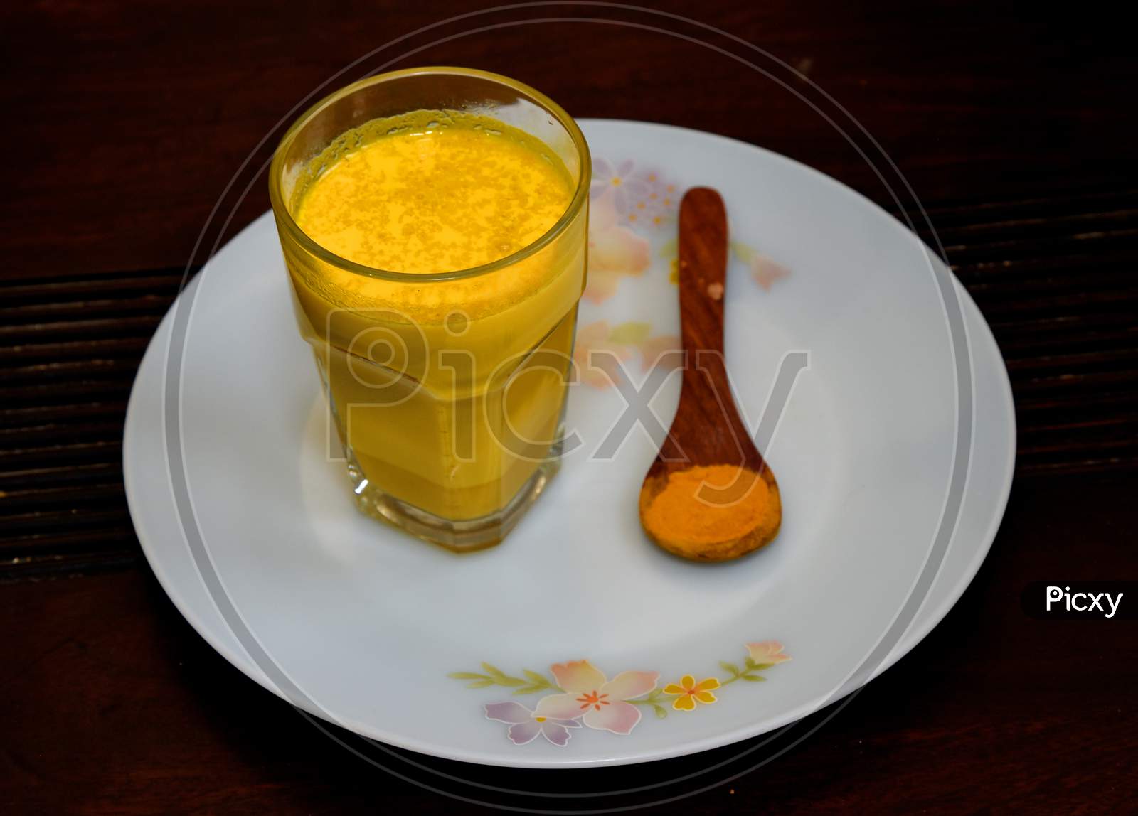 Turmeric Milk in a Glass With a Spoon of Turmeric Powder