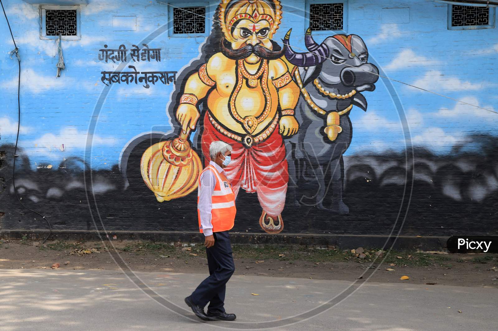 A Railway Employee Walk In Front Of Wall Painting Of Yamraj During A Nationwide Lockdown To Slow The Spreading Of The Coronavirus Disease (Covid-19), In Prayagraj, April, 17, 2020.