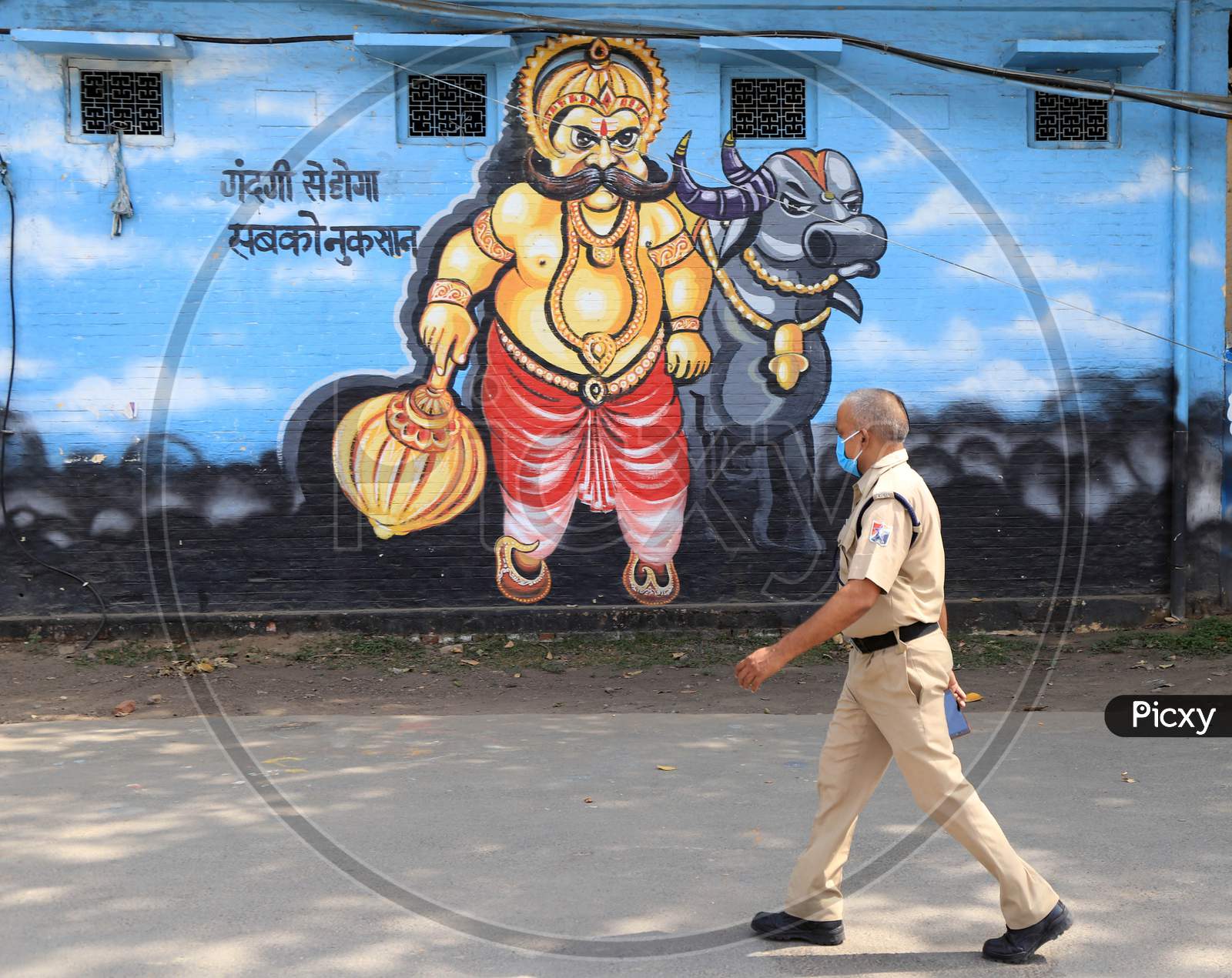 A Rpf Jawan Walk In Front Of Wall Painting Of Yamraj During A Nationwide Lockdown To Slow The Spreading Of The Coronavirus Disease (Covid-19), In Prayagraj, April, 17, 2020.