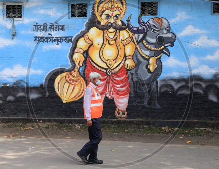 A Railway Employee Walk In Front Of Wall Painting Of Yamraj During A Nationwide Lockdown To Slow The Spreading Of The Coronavirus Disease (Covid-19), In Prayagraj, April, 17, 2020.