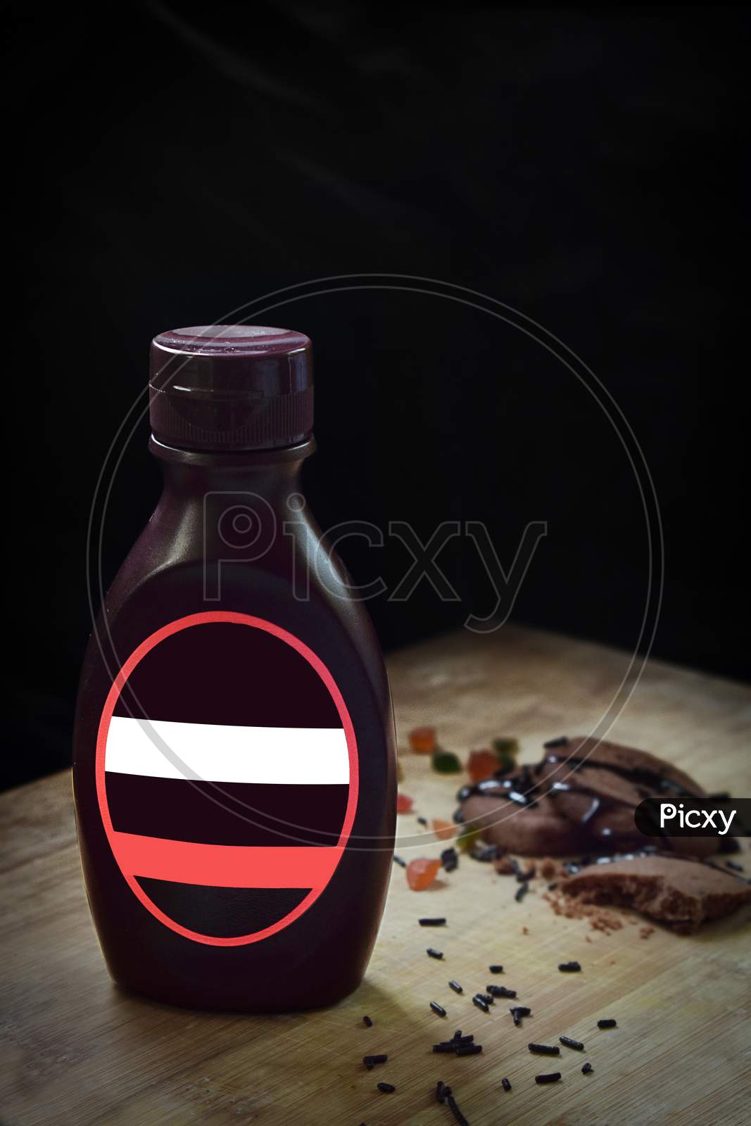 A chocolate sauce bottle without any tag of company with dark black background.