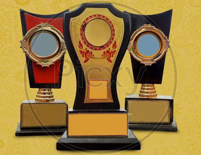 Three trophies - golden orange and black colored in golden textured background royal design