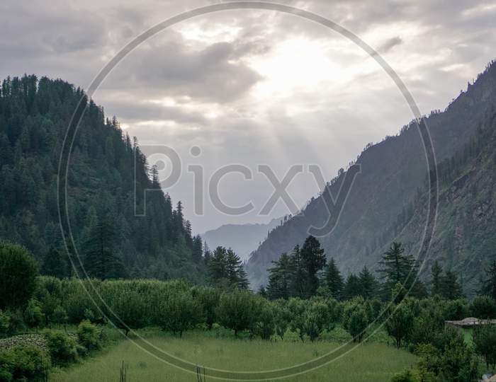 Sun Rays Coming Out From Clouds In Mountains. Nice Green View Of Mountain Valley
