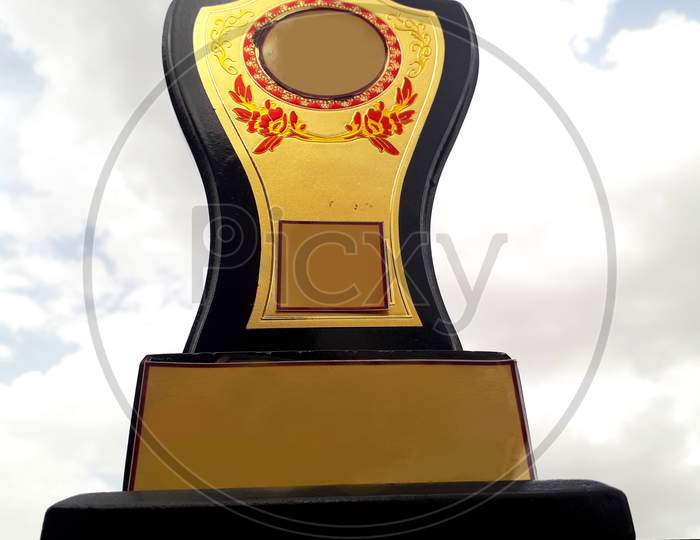 An orange colored trophy  isolated in golden textured background with attractive design