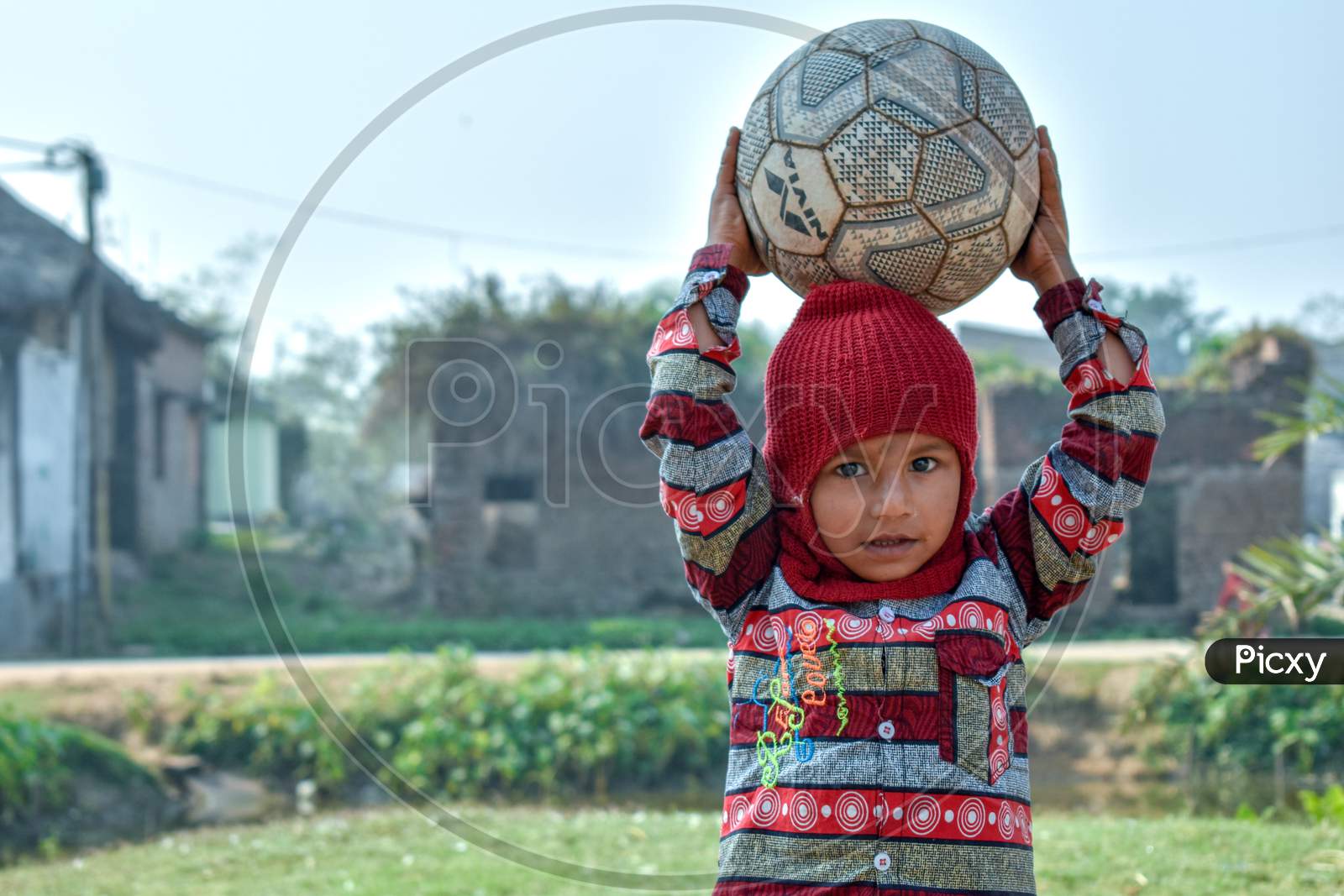 A 4-year-old poor child of a village is playing with a football