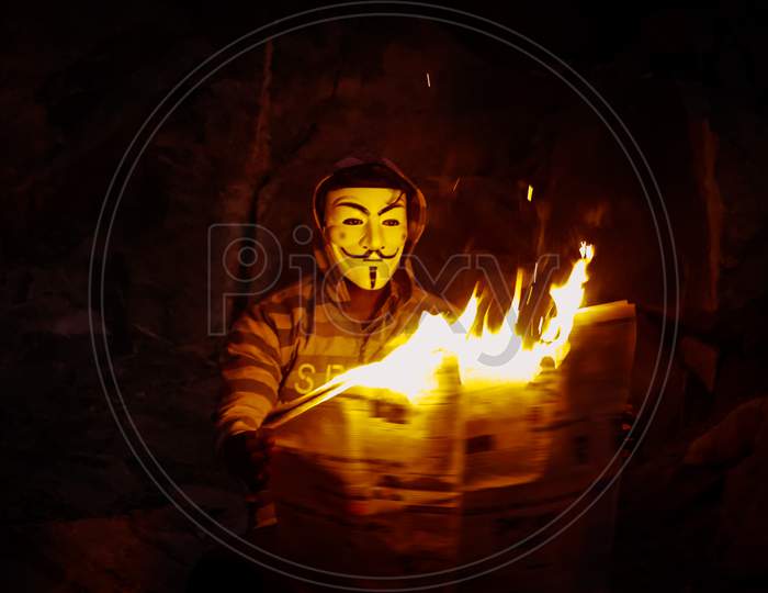 A man with mask reading a burning newspaper  