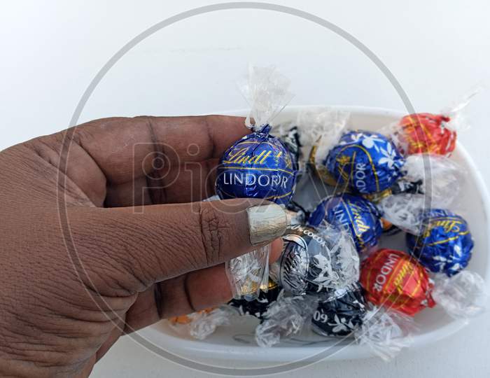 Indian woman picking  Lindt Lindor assorted chocolate from a bowl
