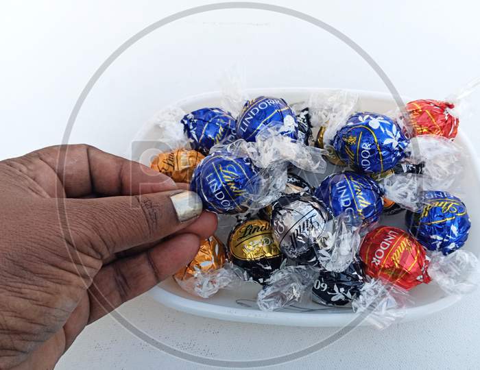 Indian woman picking  Lindt Lindor assorted chocolate from a bowl