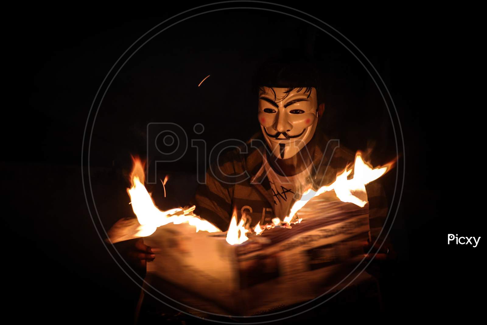 A man with mask reading a burning newspaper  