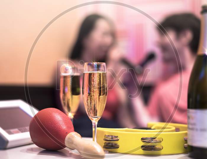 Red Maraca In Karaoke Club, With Champagne Bottle And Couple Of Sparkling Wine Glasses, Yellow Tambourine And Screen For Singing Music On Romantic Stage Party.