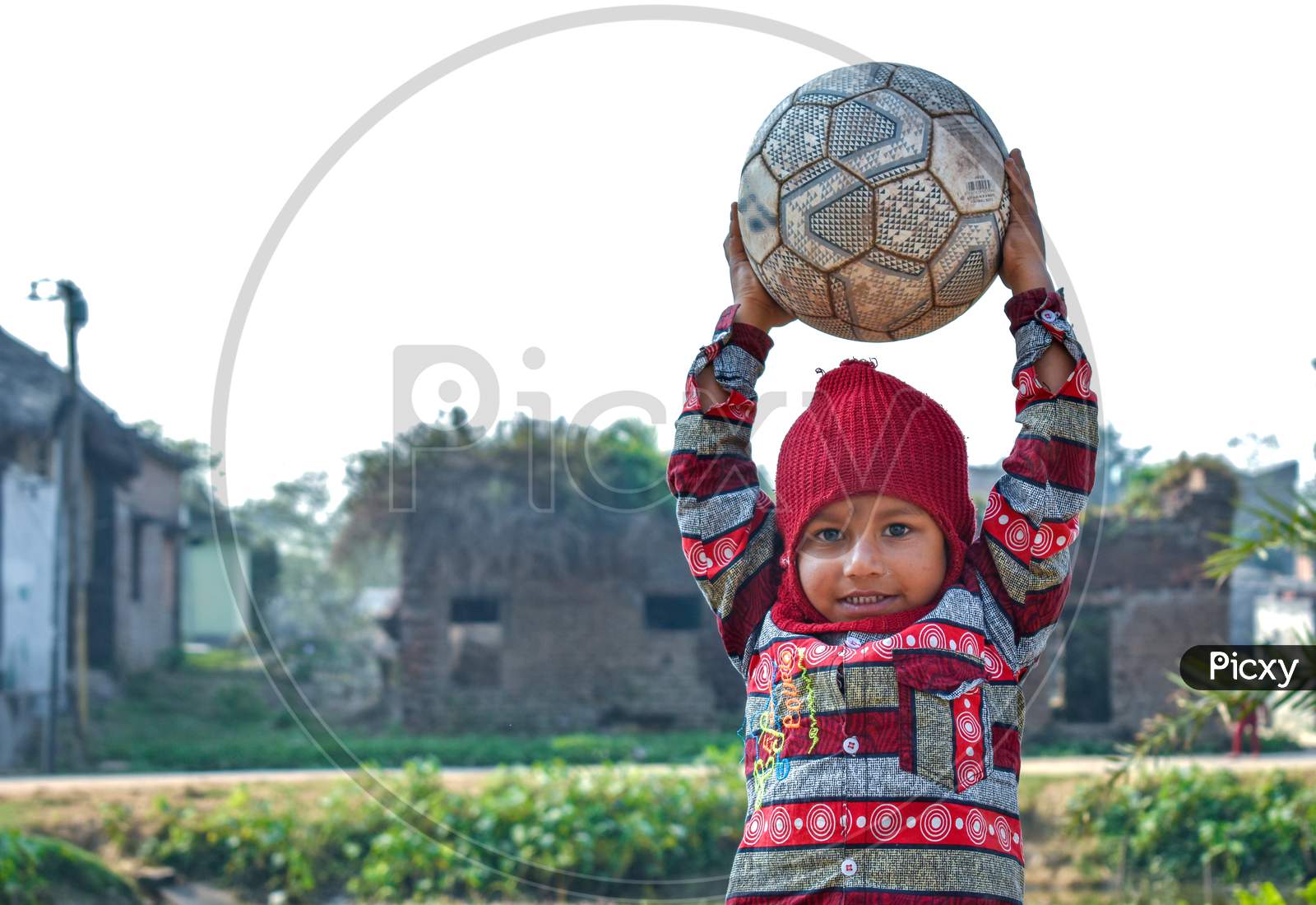A 4-year-old poor child of a village is playing with a football