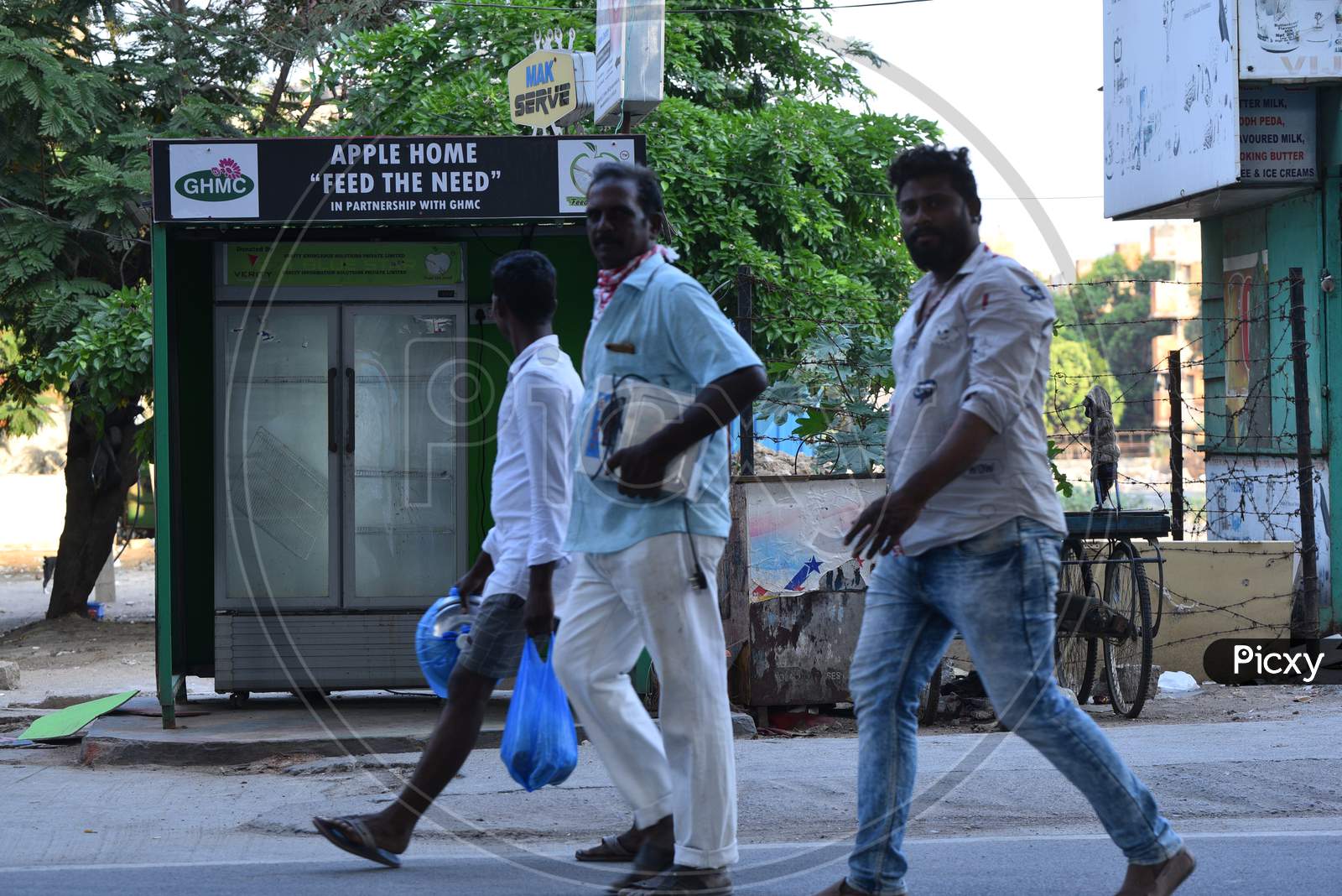 men walk past a 'feed the need' fridges installed by GHMC