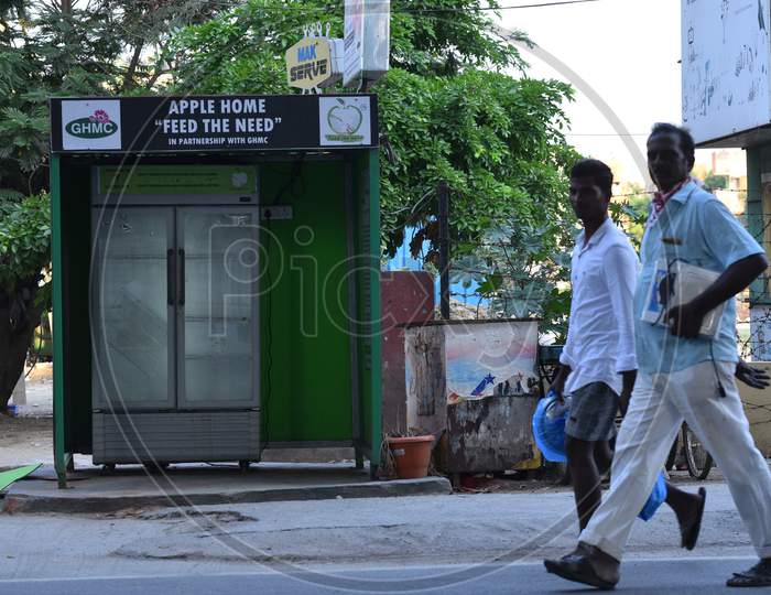 men walk past a 'feed the need' fridges installed by GHMC