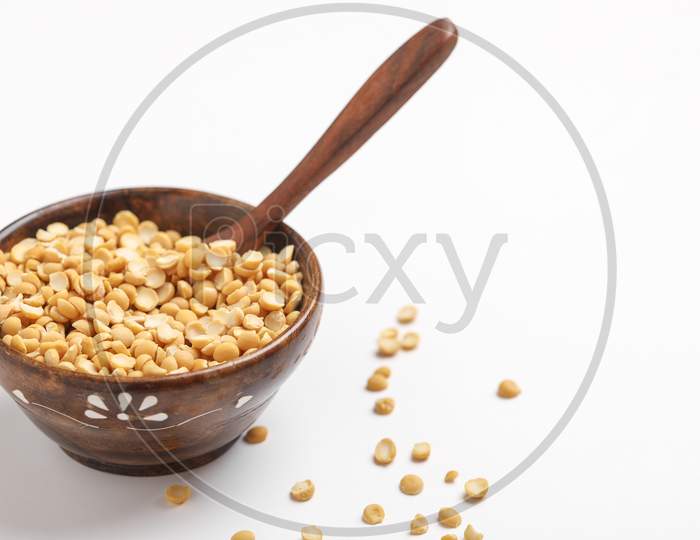 Dried Chickpea Lentils In Wooden Bowl And Spoon On White Background , Split Chickpea Also Know As Chana Dal ,
