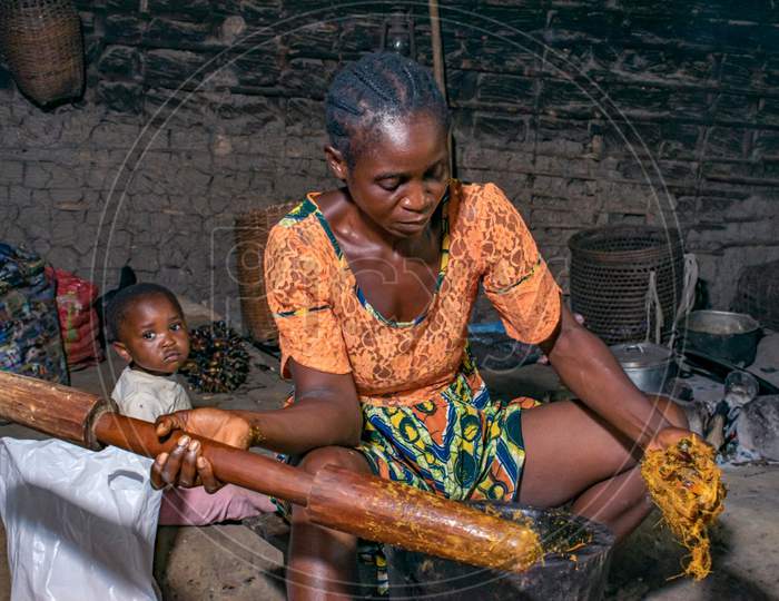 Mother preparing red oil from palm kernels to cook for her home, African kitchen