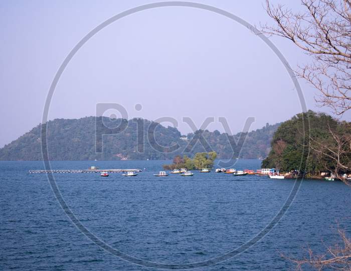 A Beautiful Lake With An Island Beside It And Boats Parked Near The Bay