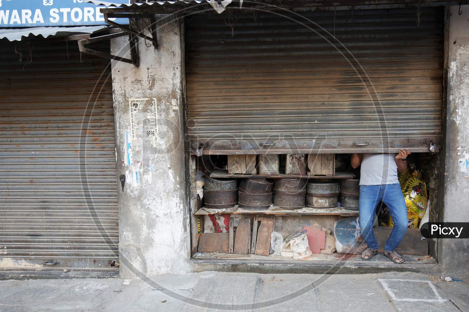 A Flour Mill Shopkeeper Closing Shop Shutter As per Lockdown Rules During Corona Virus ( COVID-19) Pandemic In Bangalore City