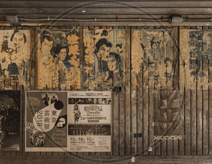 Old Vintage Retro Japanese Movie Posters On Underpass Yurakucho Concourse Wall Under The Railway Line Of The Station Yurakucho. Japanese Noodle Stalls And Sake Bars Revive The Nostalgic Years Of Showa Air With Old Samurai Posters And Placards Glued To The Walls Of The Tunnel.