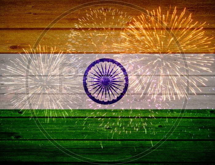 Indian flag painted on wooden texture with fireworks background.