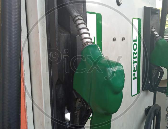 Petrol nozzle in green colour in a petrol filling station in India.