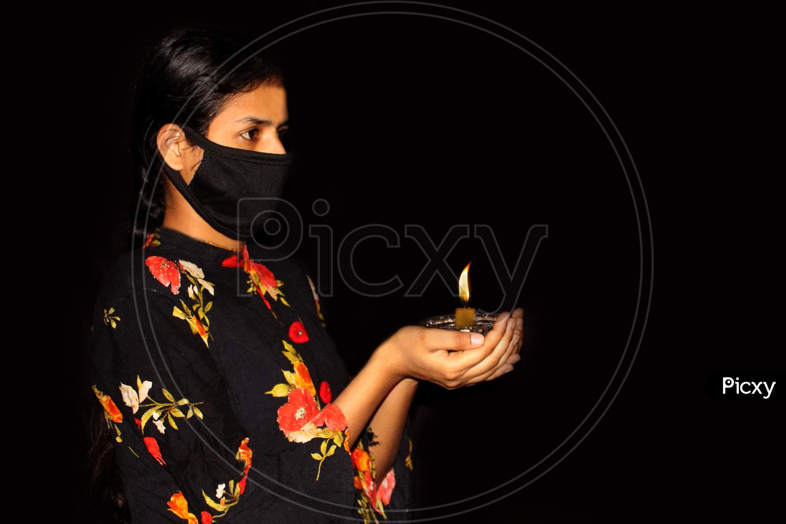 portrait of covid 19 infected sad woman hand holding burning candle for prayer  in dark background